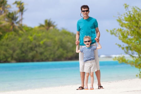 handsome father and his little son having fun together at the beachの写真素材