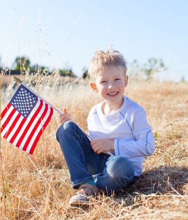 cute little boy holding american flag and celebrating independence dayの写真素材