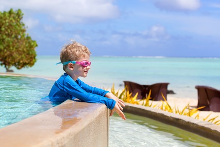 little boy relaxing in the swimming pool and enjoying the viewの写真素材