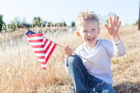 cute little boy holding american flag and celebrating independence dayの写真素材