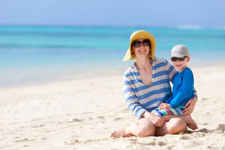 beautiful mother and her little son sitting at the beach togetherの写真素材