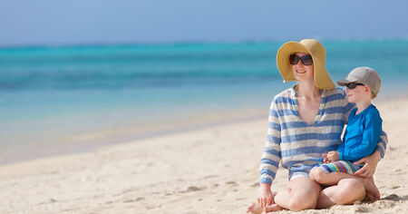 beautiful mother and her little son sitting together at the beach, vacation togetherの写真素材
