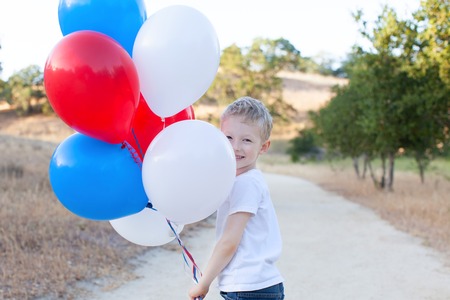 little cheerful boy holding colorful balloons and celebrating 4th of Julyの写真素材