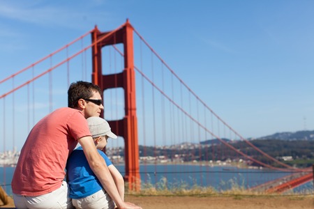 young father and his son sitting and enjoying view at golden gate bridge, san francisco, californiaの写真素材