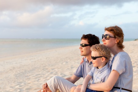 family of three enjoying sunset at the beachの写真素材