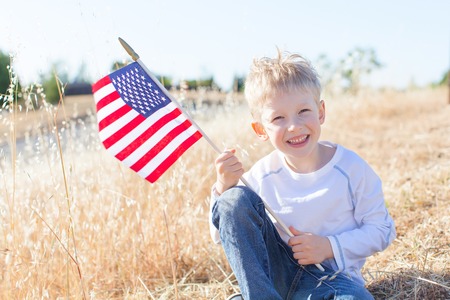 little boy holding american flag and celebrating 4th of Julyの写真素材