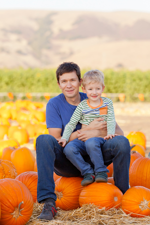 happy young father and his cute son spending fun time together at pumpkin patch; family of two at fallの写真素材