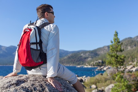 young healthy man resting at the top of the rock after hiking near lake tahoe, california, usaの写真素材