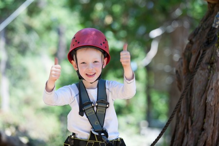 brave little boy having fun at adventure park and giving double thumbs-upの写真素材