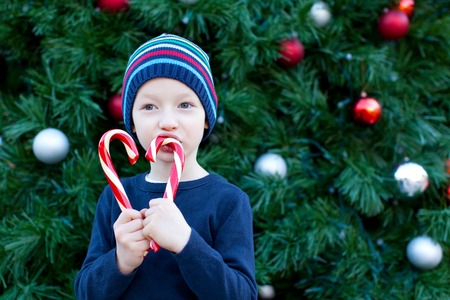 happy little boy holding candy canes at christmas timeの写真素材