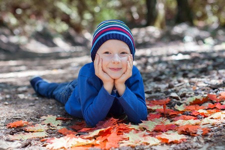 cheerful little boy having fun at autumn time in the forestの写真素材