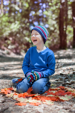 handsome little boy in the forest at fall timeの写真素材