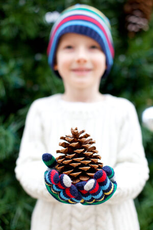close-up of cute little boy holding cone by the christmas treeの写真素材