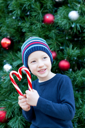 funny little boy playing with candy canes at christmas timeの写真素材