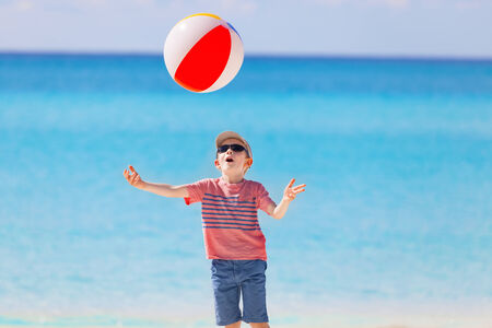 cheerful little boy playing with the ball at the caribbean beautiful beachの写真素材