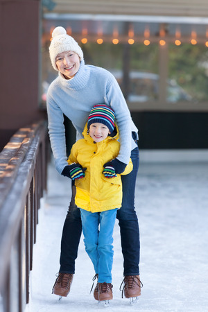 happy mother and her little son having fun ice skating together at winterの写真素材