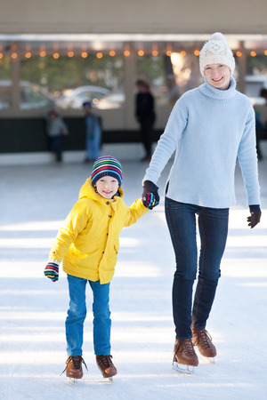 happy mother and her little son having fun ice skating together at winterの写真素材