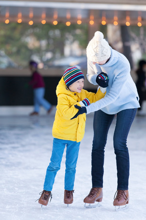 happy mother and her little son having fun ice skating together at winterの写真素材