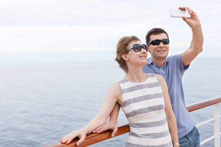 young couple taking selfie with smartphone while cruising, vacation conceptの写真素材