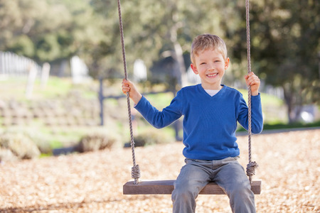 adorable little boy swinging in the parkの写真素材