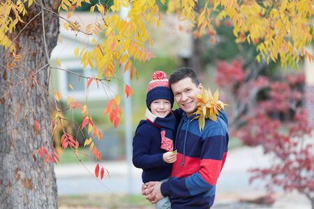 cute smiling boy and his father enjoying autumn weather at the parkの写真素材