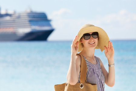 young smiling woman enjoying beach vacation with cruise ship in the backgroundの写真素材