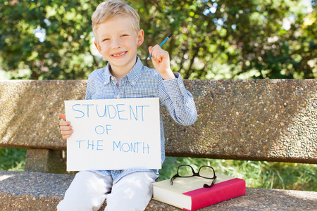 smiling boy holding student of the month sign ready for school yearの写真素材