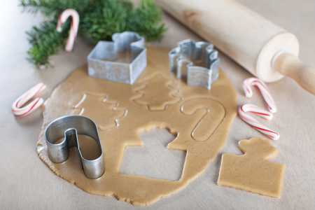 rolled dough with christmas themed cookie cutters and rolling pin, candy canes and christmas tree branches in the background, christmas or new year time conceptの写真素材