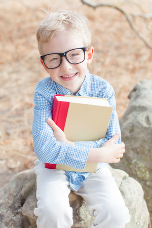 smiling schoolboy in glasses studying ready for school enjoying warm weather in the parkの写真素材