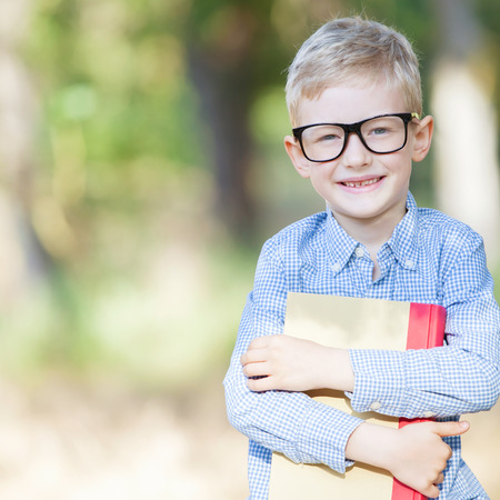smiling schoolboy in glasses studying ready for school enjoying warm weather in the parkの写真素材
