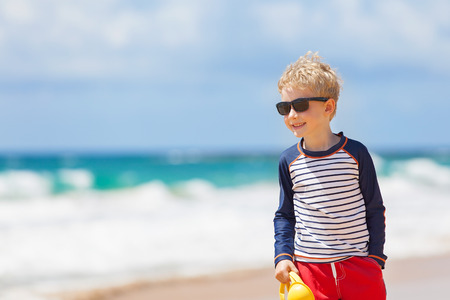 smiling beautiful boy enjoying summer vacation at the beach at kauai island, hawaiiの写真素材