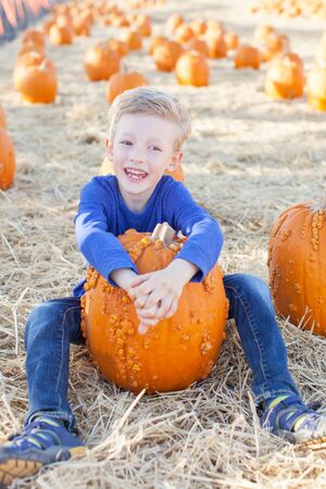 smiling 6-year old boy having fun and enjoying autumn time at pumpkin patchの写真素材