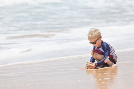 little boy playing at kealia beach at kauai island, hawaiiの写真素材