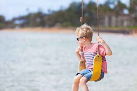 little cute boy at swings enjoying summer vacationの写真素材