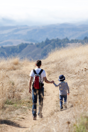 back view of young father and his little son hiking in the park enjoying day togetherの写真素材