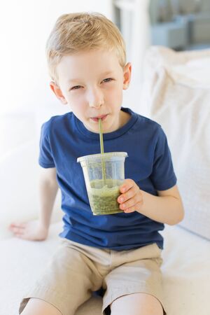 portrait of beautiful smiling boy enjoying healthy smoothie and relaxing during vacationの写真素材