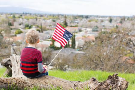back view of patriotic boy holding american flag and celebrating 4th of julyの写真素材