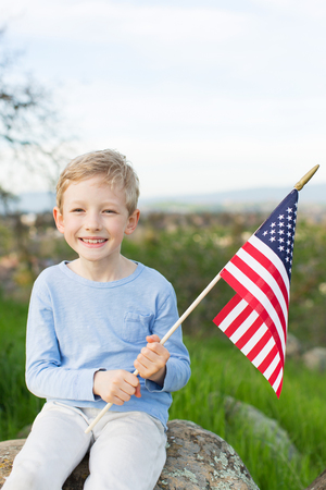 smiling boy holding american flag and celebrating 4th of julyの写真素材