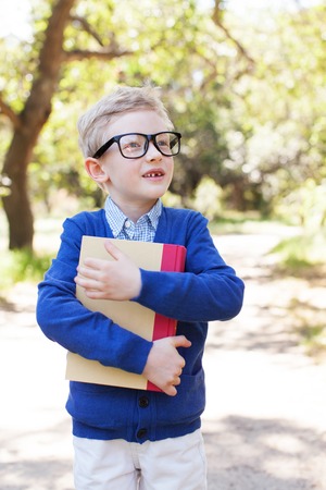 smart little boy in glasses holding book ready for schoolの写真素材