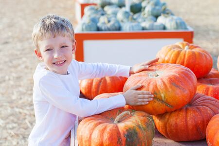 beautiful boy enjoying autumn time at pumpkin patchの写真素材
