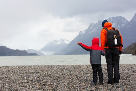 active father and his son enjoying the view of glacier grey at lago grey and having adventure hike at torres del paine national park, patagonia, chileの写真素材