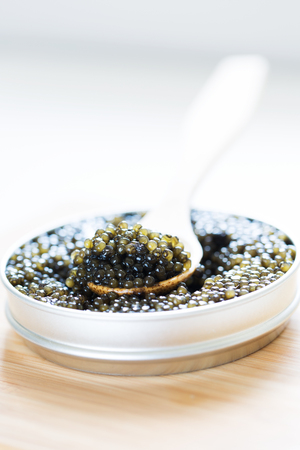 close-up view of metal tin with black sturgeon caviar and wooden spoon on itの写真素材