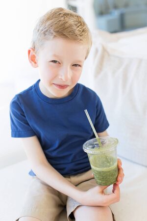 smiling positive boy enjoying green healthy smoothieの写真素材