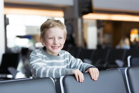 cheerful positive smiling boy at the airport waiting for departure, travel and vacation conceptの写真素材