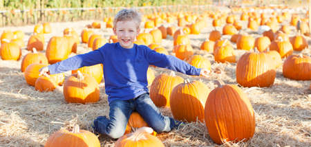 panorama of positive cheerful boy enjoying pumpkin patch at fall pretending to be a plane being playfulの写真素材