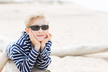 smiling positive boy in sunglasses enjoying warm weather at the beach in californiaの写真素材