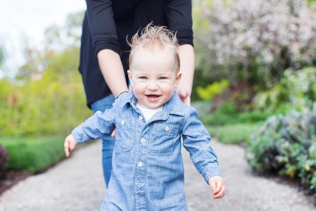 young mother and her toddler son enjoying time together in the park, little boy making his first stepsの写真素材