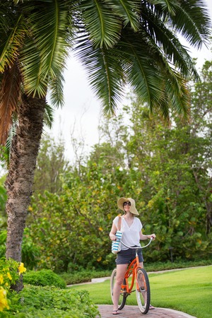 young woman with bicycle enjoying resort grounds and summer vacationの写真素材