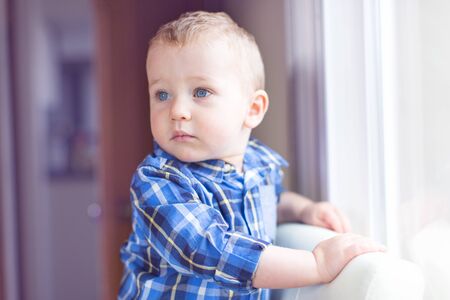 adorable toddler with blue eyes being serious and enjoying time at home, toned image