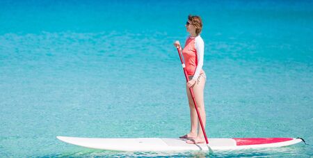 young woman enjoying stand up paddling, active and healthy summer vacation activityの写真素材